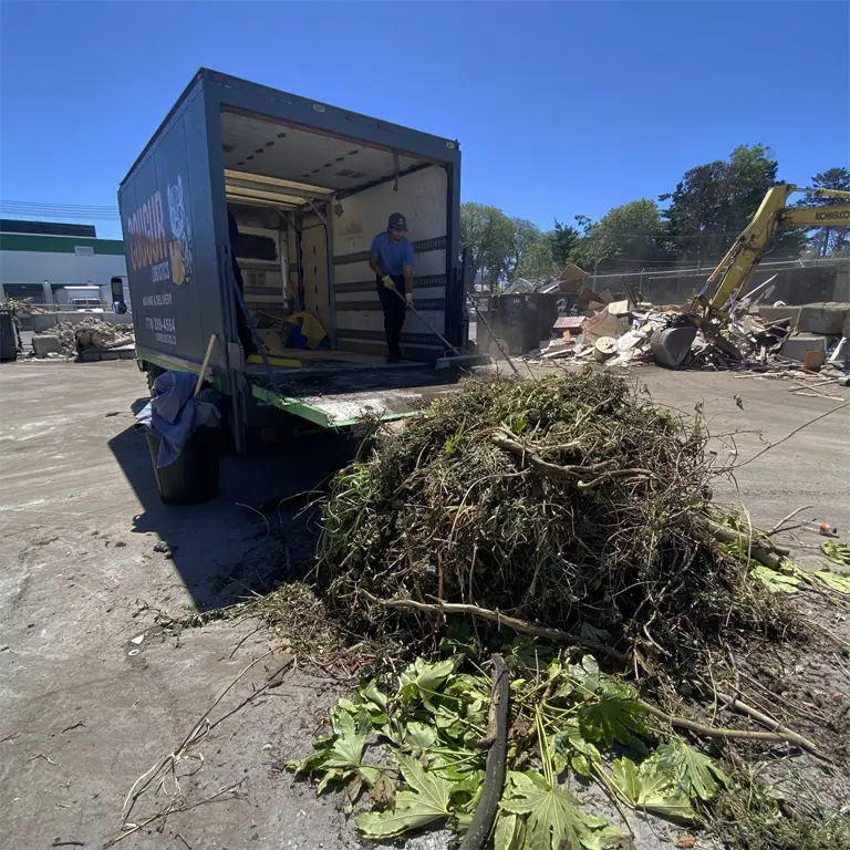 Cougur Logistics truck at a Victoria recycling facility with an employee clearing lawn trimmings from the truck.