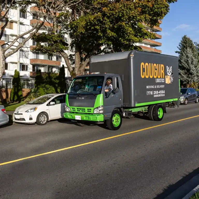 Cougur Logistics truck driving past a care home on Dallas Road in Victoria, BC.