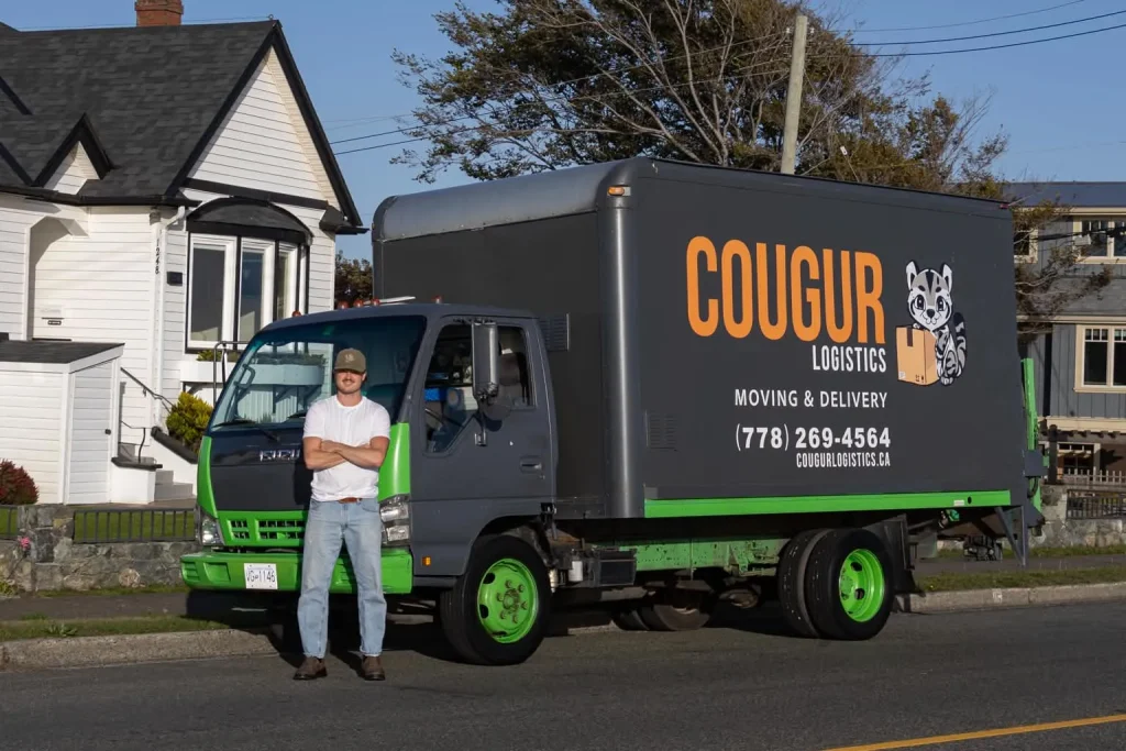 Cougur Logistics mover standing in front of the company 16-foot moving truck in Victoria